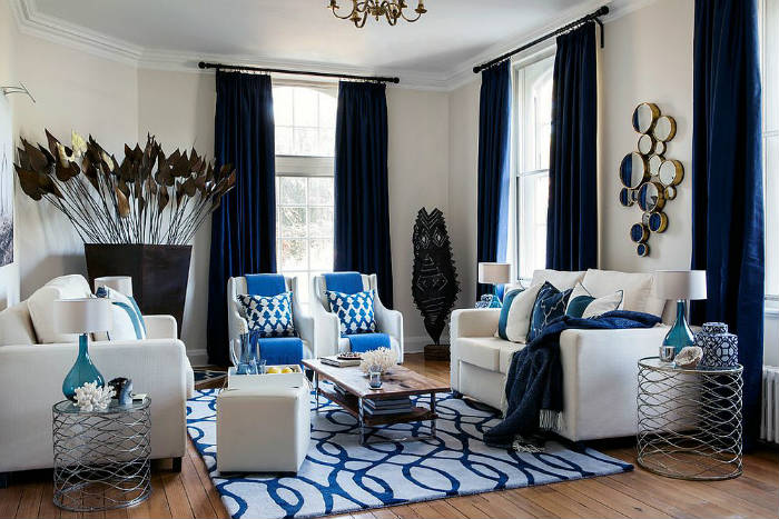 Σκούρες μπλε κουρτίνες σε σαλόνι με έμφαση στο λευκό και το μπλε.