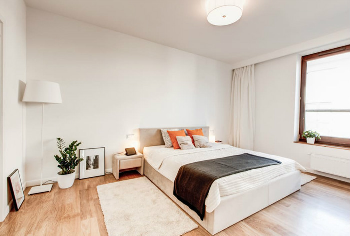 Στο υπνοδωμάτιο το φυτό και τα πορτοκαλί μαξιλάρια χαρίζουν χρώμα.