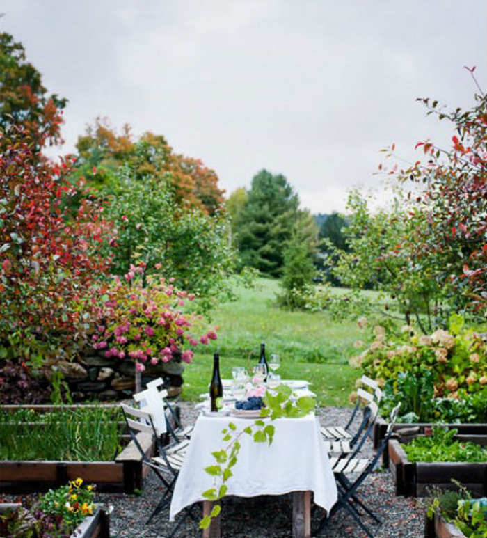 Στο αγρόκτημα του Vermont βλέπεις παρτέρια με λαχανικά και τριανταφυλλιές και έναν πανέμορφο κόκκινο κέδρο στα αριστερά.