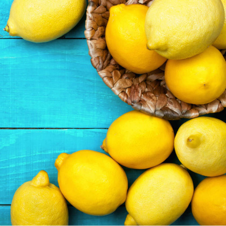 Λεμόνια σε καλάθι και τυρκουάζ τραπέζι.