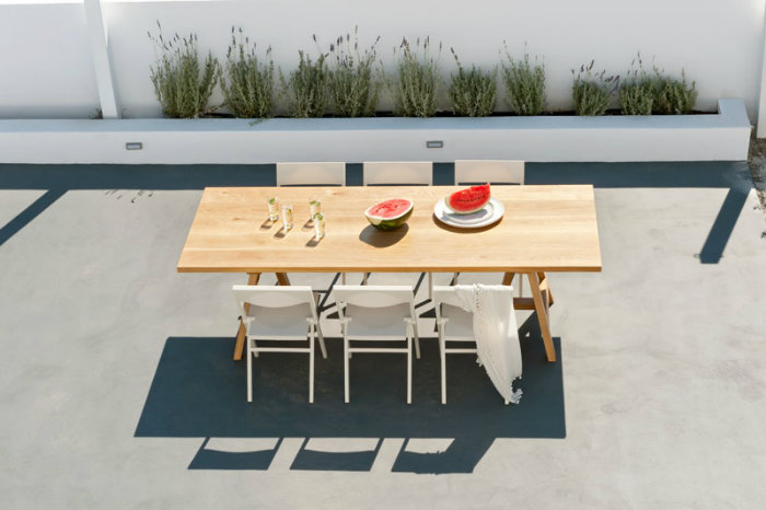 Μια εξωτερική τραπεζαρία με λευκές καρέκλες και λεβάντες στο κηπάκι πίσω, αποτελεί το τέλειο σκηνικό χαλάρωσης.