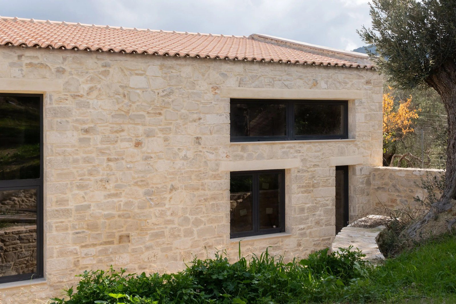 Πέτρινη όψη με μακρύ οριζόντιο παράθυρο ψηλά, μικρότερο παράθυρο από κάτω και ανοιχτόχρωμα πέτρινα πρέκια