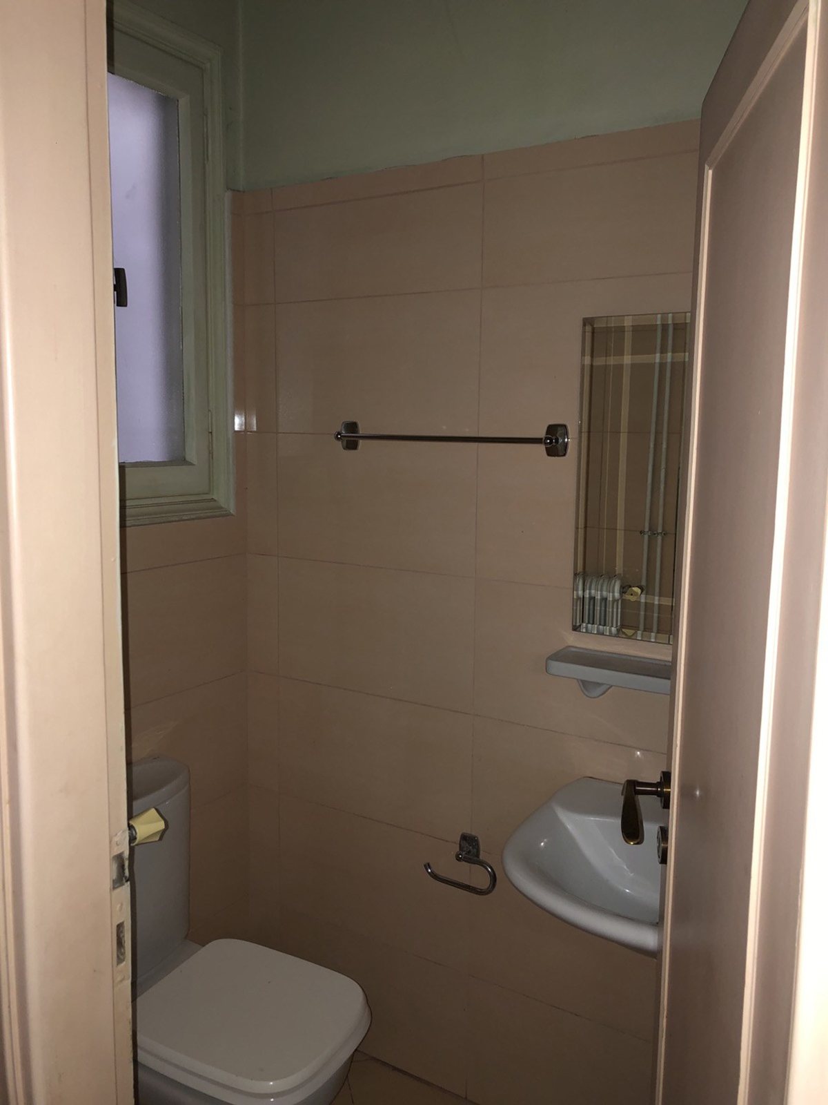 Παλιό WC με ροζ πλακάκια, μικρό νιπτήρα, λεκάνη και στενό παράθυρο, πριν από την ανακαίνιση