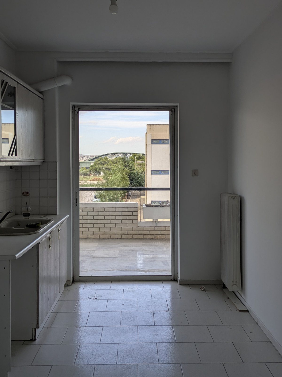 Η παλιά κλειστή κουζίνα του διαμερίσματος με λευκά πλακάκια και μπαλκονόπορτα πριν την ανακαίνιση